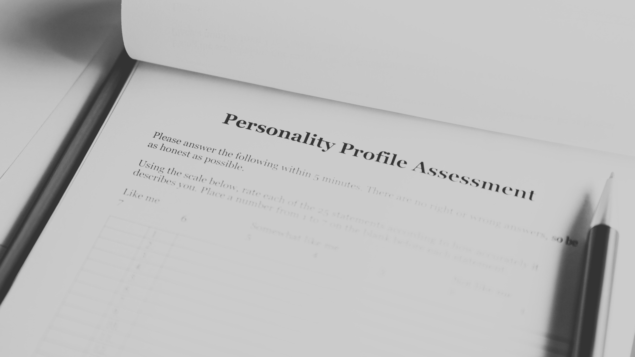 Black and white close-up of a personality profile assessment form with a pen, representing advanced psychometric evaluation for workforce development.