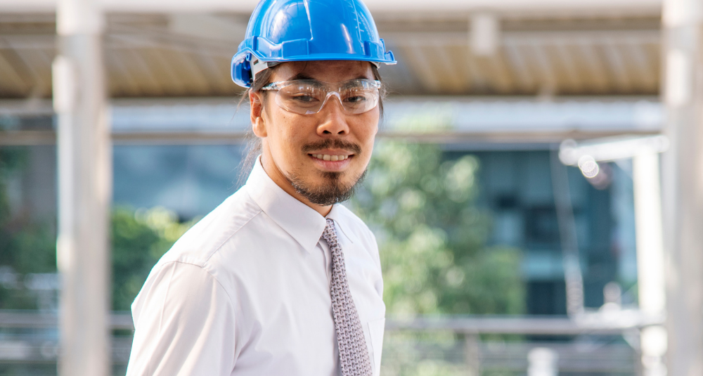 A man wearing formal wear and a hard hat, representing a project manager