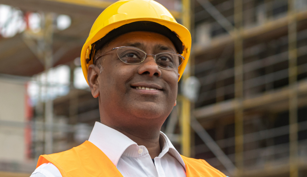 A man wearing formal wear and a hard hat, representing a senior protection and automation technician